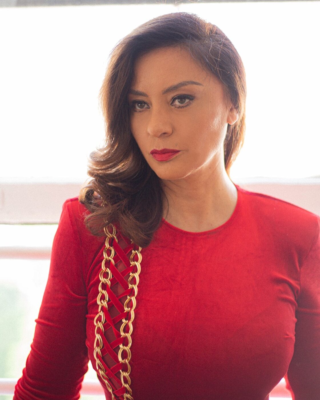 Paulina Aguirre, founder of The Amazonia, in a red dress against a bright window.